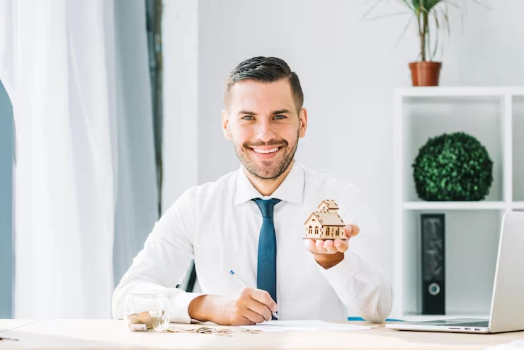 Property acquisition specialist holding house model for buy and sell services in Manchester