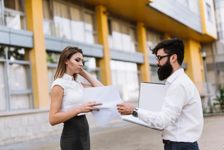 Business professionals reviewing commercial real estate documents outside modern office building