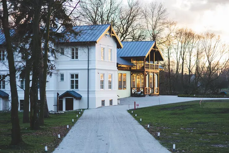 White residential property with blue roof and illuminated pathway at dusk for investment property sourcing