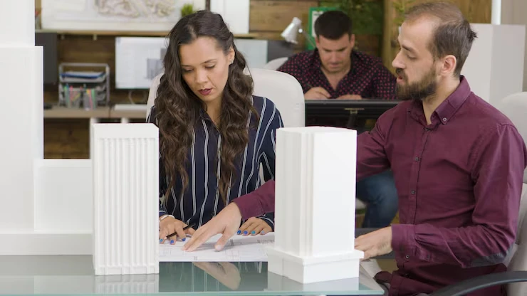 Property development team reviewing land sourcing plans and architectural models in professional office