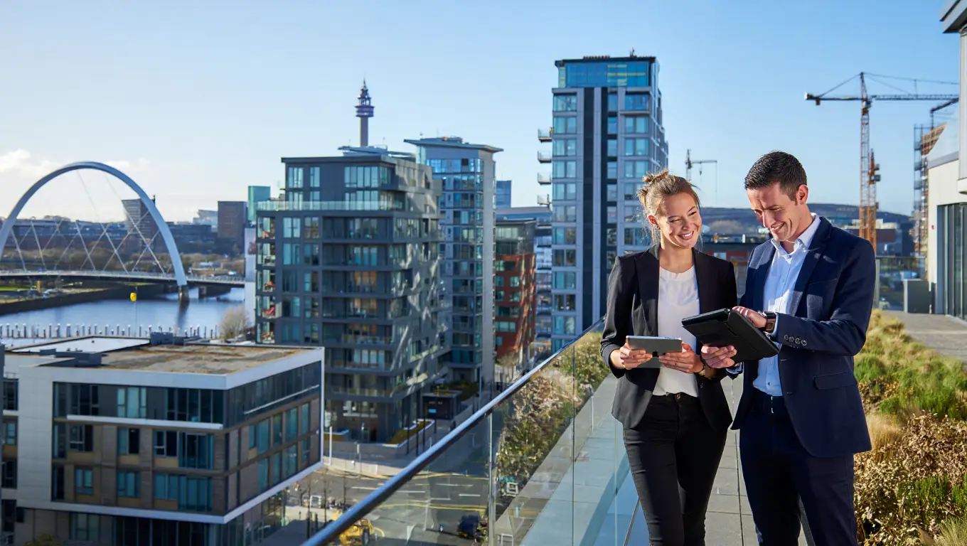 Two professionals discussing property sourcing opportunities with Glasgow city skyline background