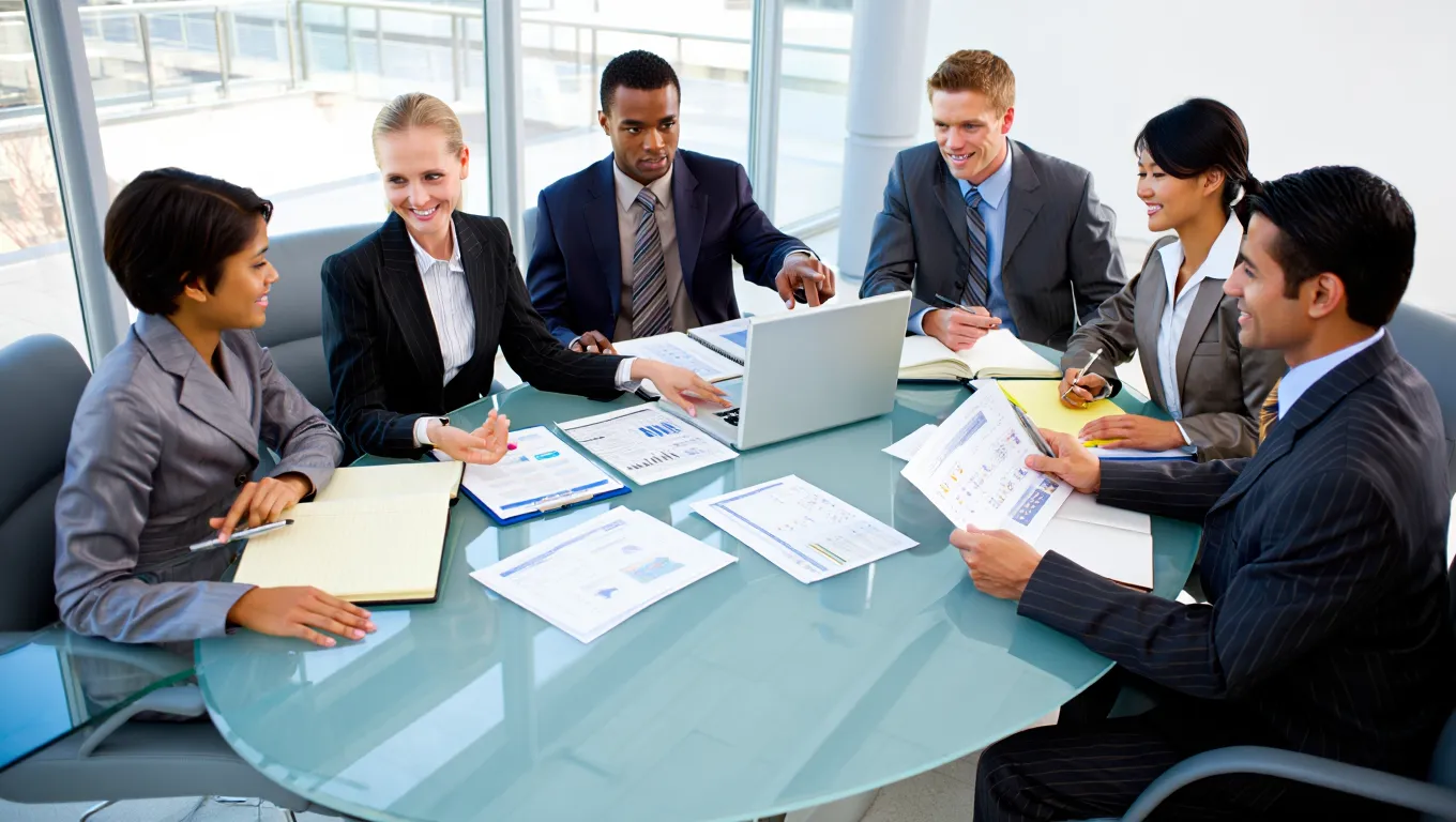Legal compliance team reviewing property documents and contracts around glass conference table