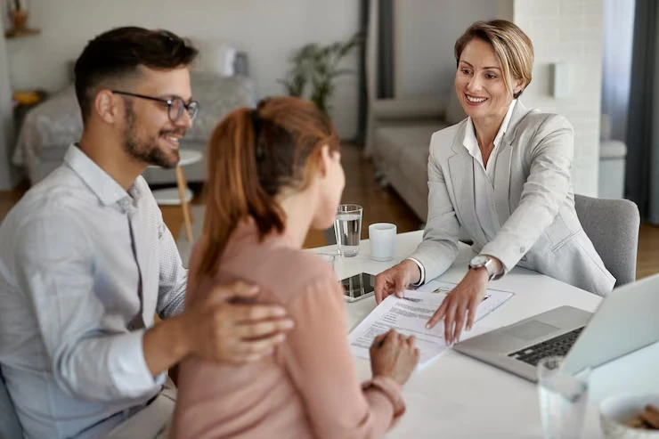 Professional advisor presenting documents to smiling couple with laptop open on bright modern table